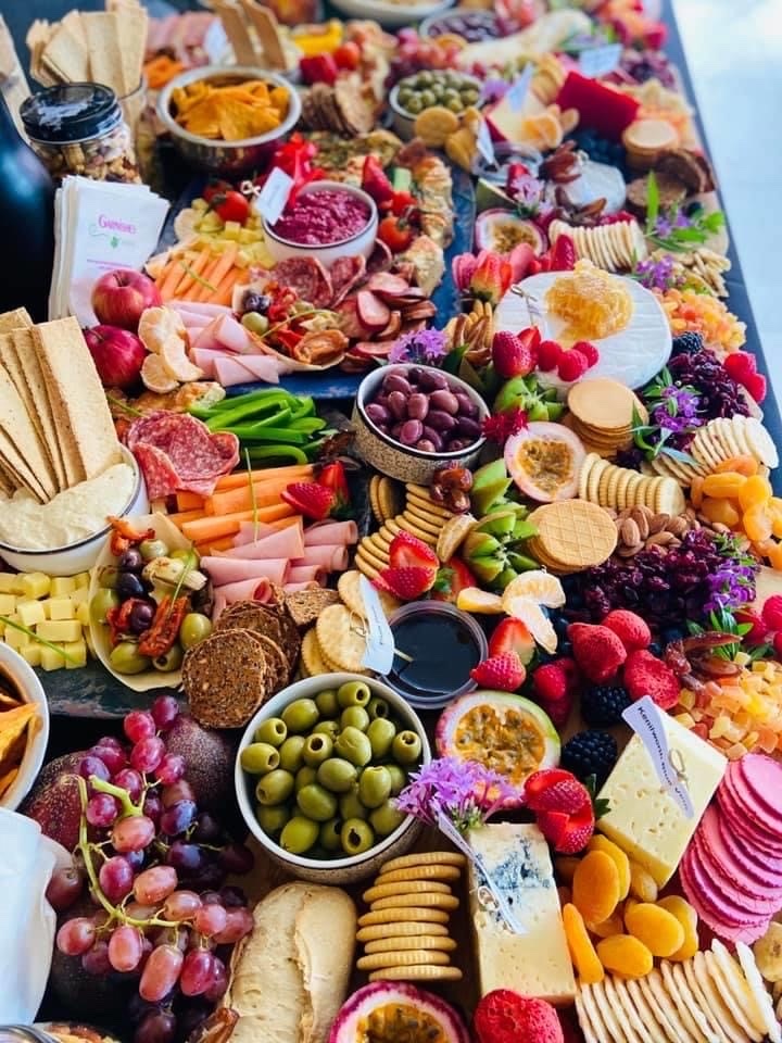 Abundant grazing table laden with cheeses, charcuterie, fruit and crackers — Garnishes grazing table catering Brisbane